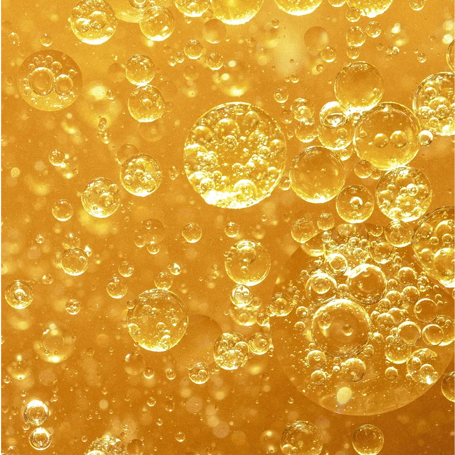 Close-up of golden bubbles of Two-Phase makeup remover a gold background
