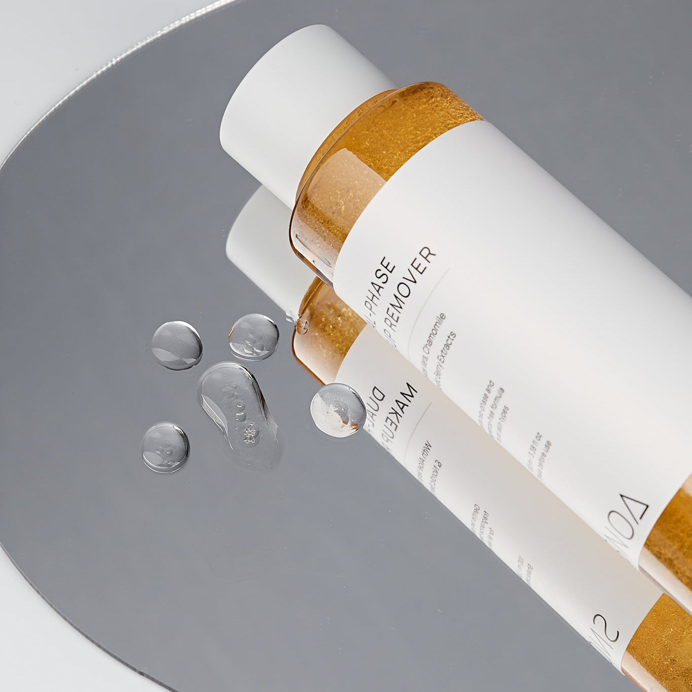Skincare bottle with droplets on a gray background